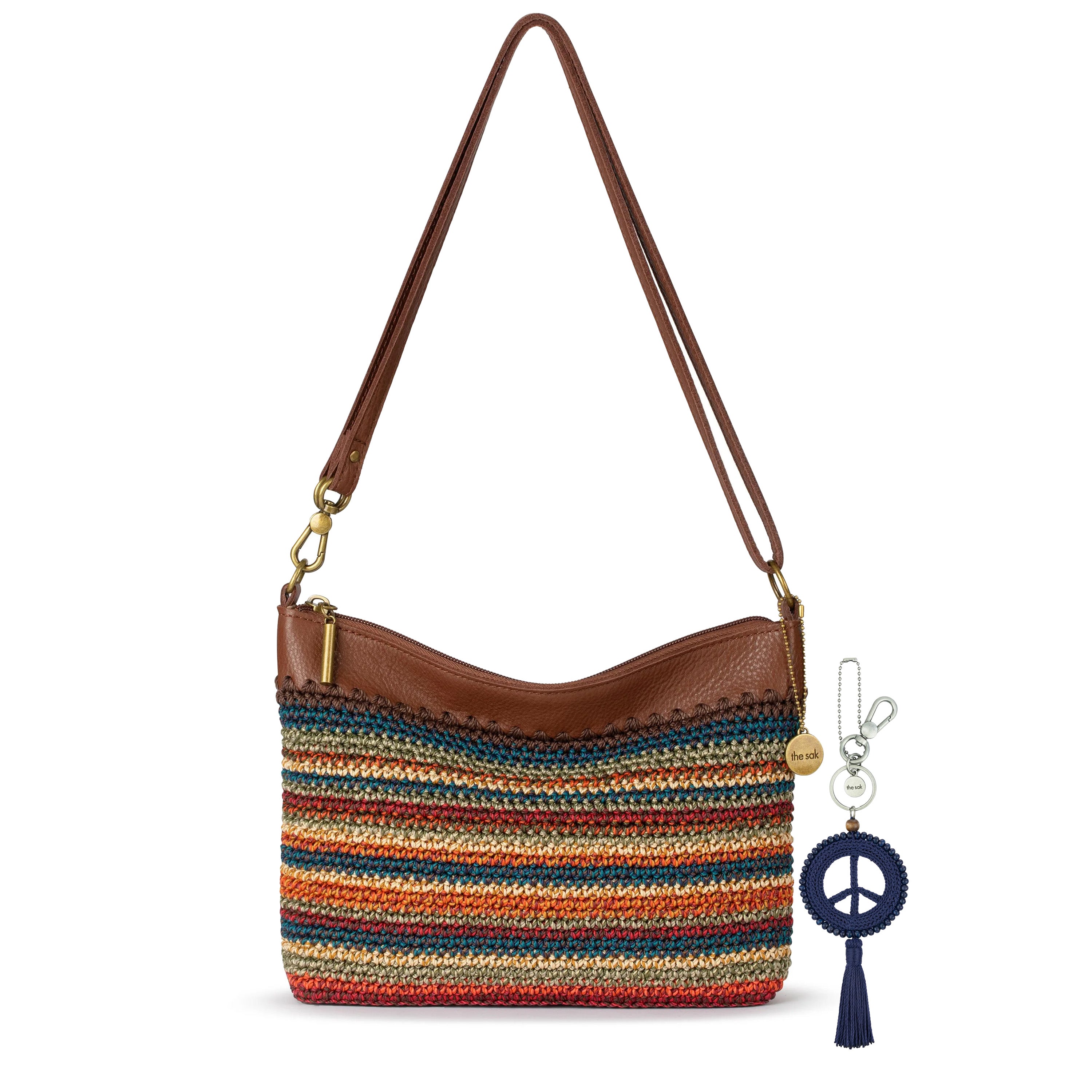 Brown leather crossbody bag with multicolor striped woven panel and dark blue peace symbol keychain dangle with tassel.